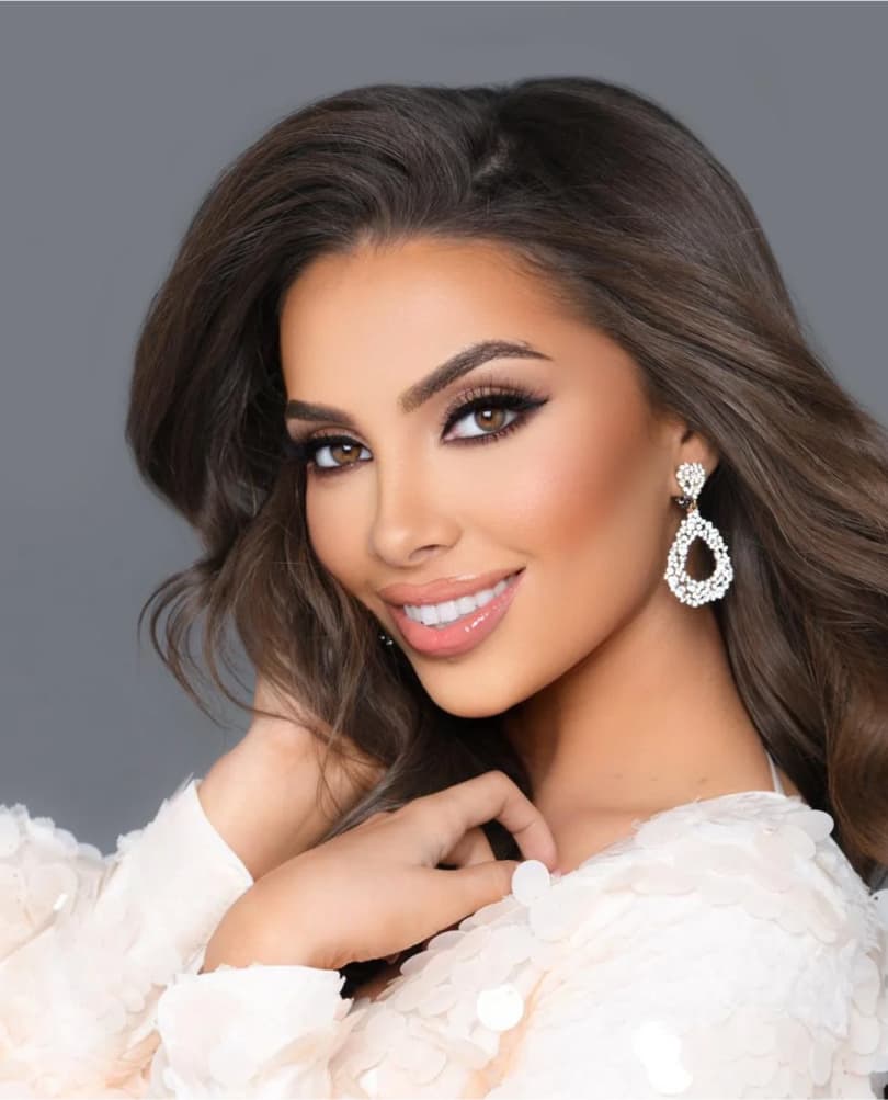 Confident woman with voluminous dark hair, wearing crystal statement earrings and glamorous makeup, representing elegance and poise at Miss Miami Pageants.